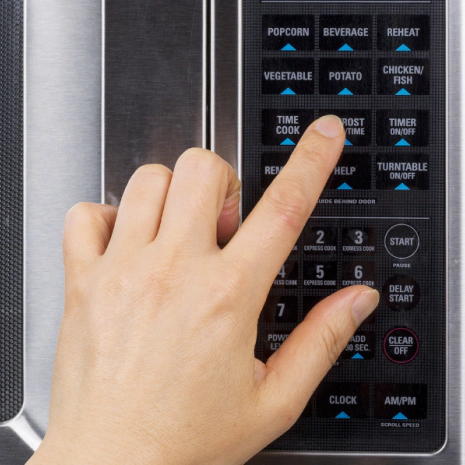 a hand navigating through the microwave buttons square